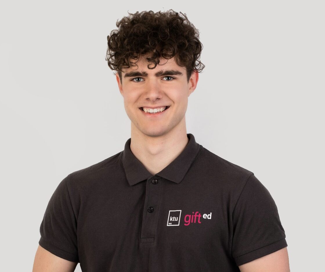 A guy with dark hair and dark grey t-shirt standing in white background