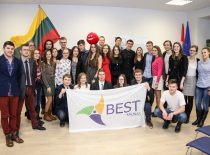 Students holding Lithuanian and BEST Kaunas flags in the conference hall.