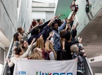 Students standing on the stairs in the Santaka Valley, holding out their arms and trying to take the ESN symbol from the student standing at the top.