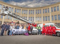 A group of students took pictures at the fire station building with police officers, emergency specialists and firefighters and their cars.