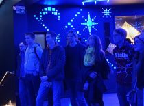 In the blue-lit room, students watch the exhibit.