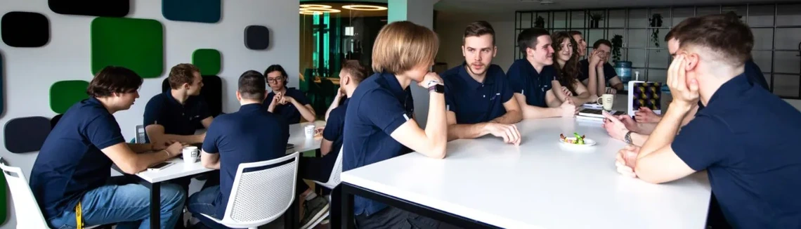 University students sitting next to two tables, chatting, wearing SKILLed merch